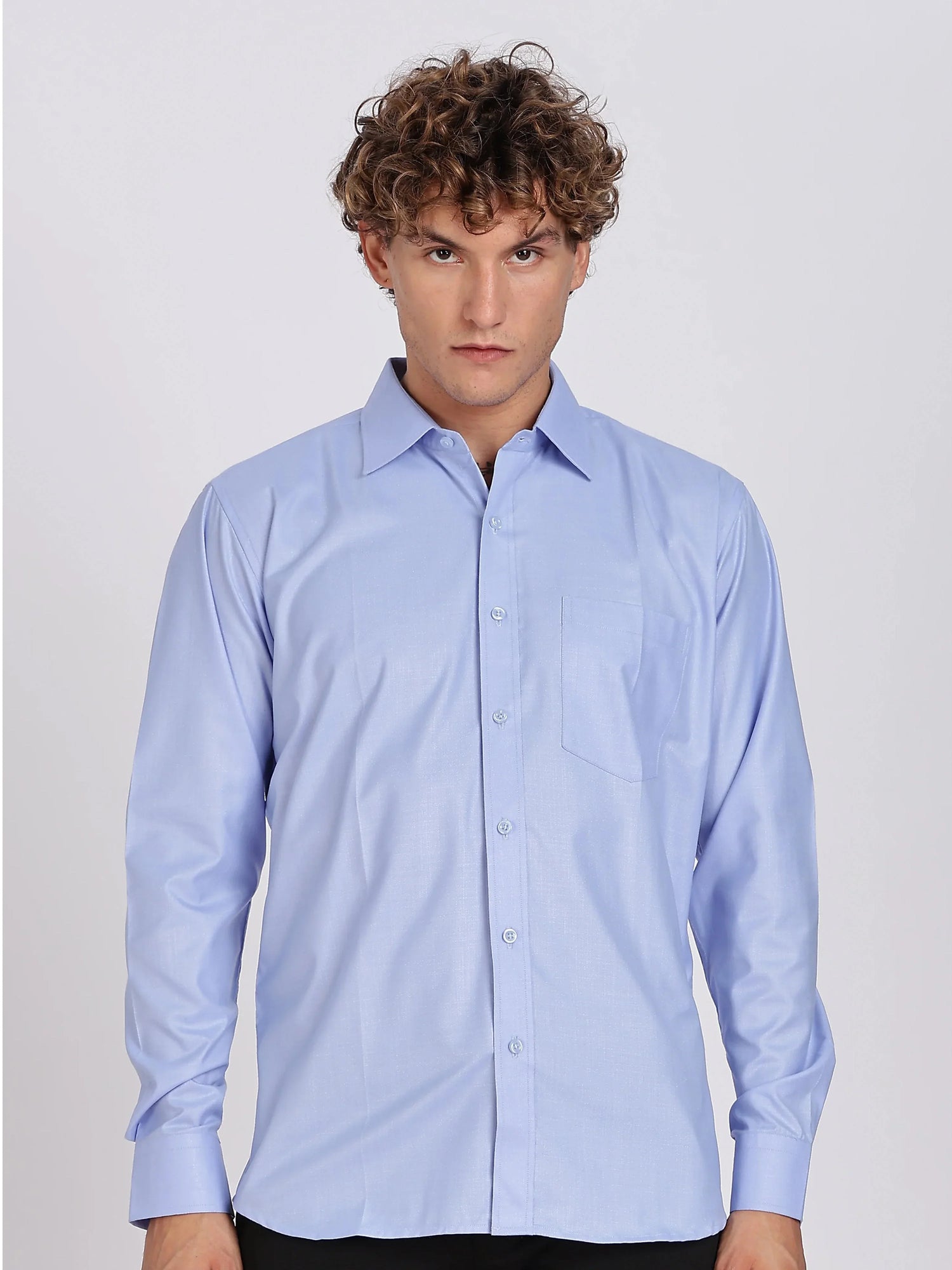 Young man wearing a light blue formal long-sleeve shirt with a front pocket on white background